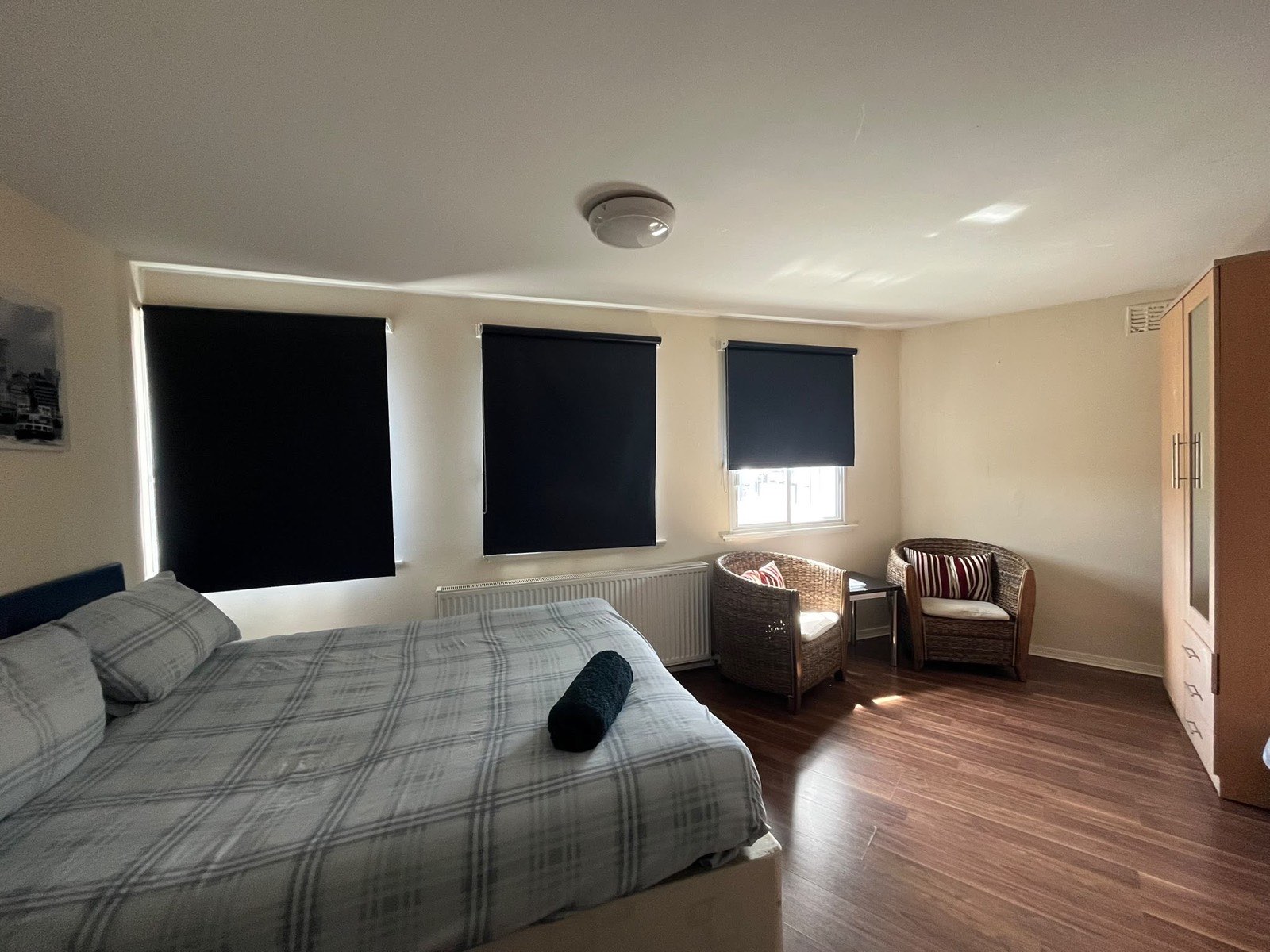 The Double room with a made-up double bed, wicker chairs and blackout blinds