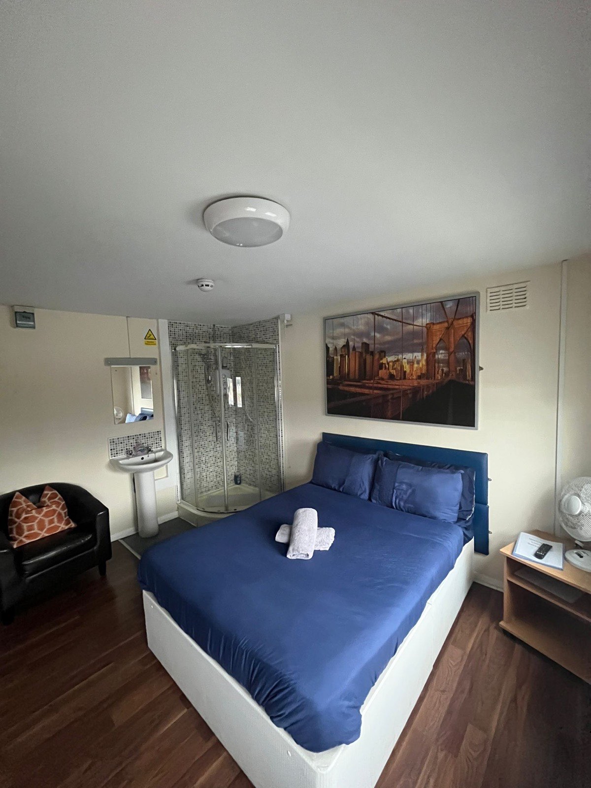 A double room with a city print and a corner shower cubicle in the room