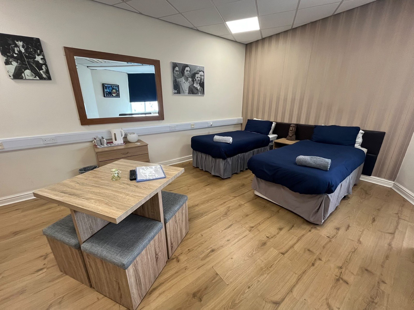 A bright, spacious guest room at Liverpool Gateway Inn with navy bedding and Beatles-era wall art